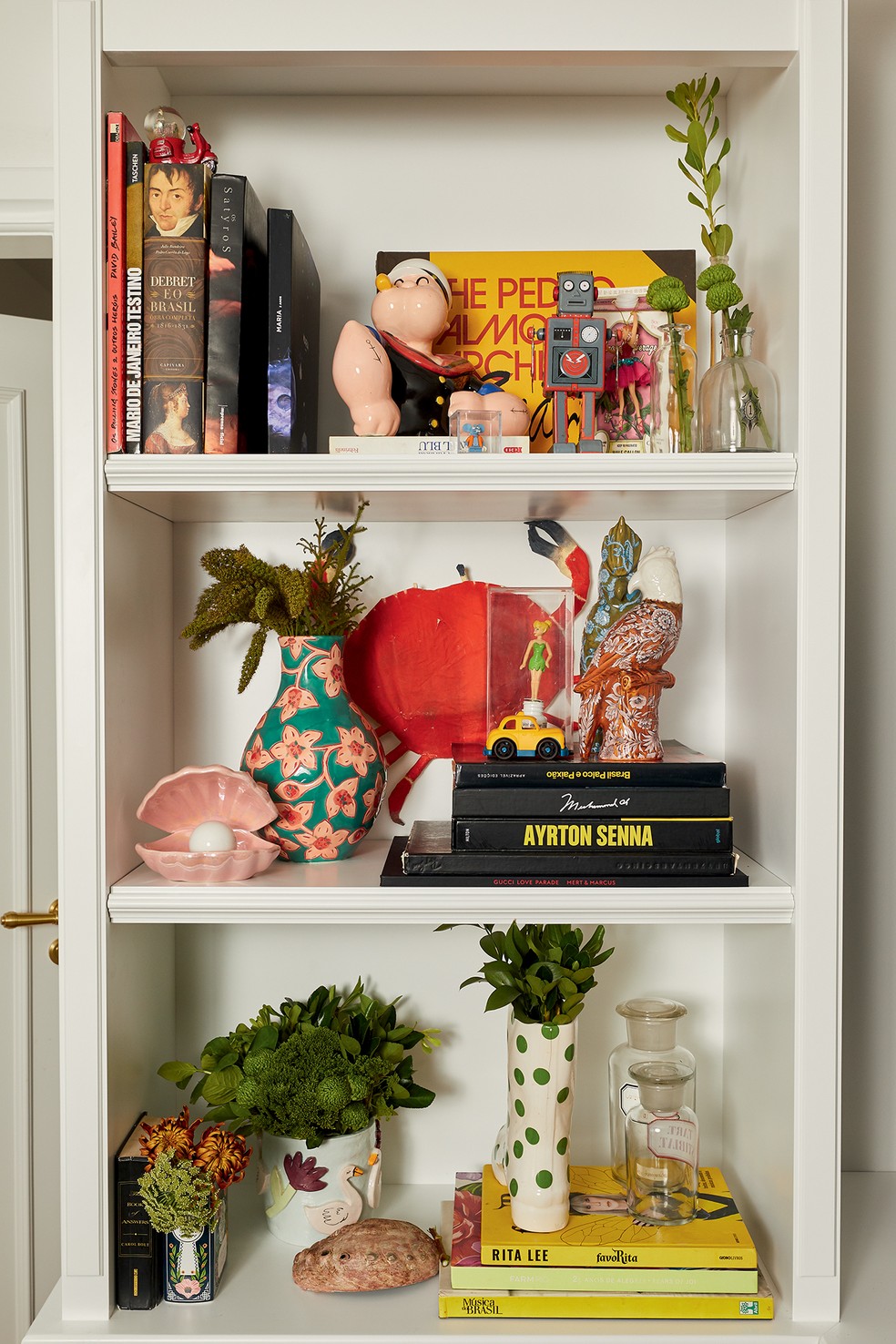 Detalhe da estante revela memórias que eles incorporaram à decoração, a exemplo de objetos encontrados em galerias e feiras mundo afora — Foto: Deco Cury
