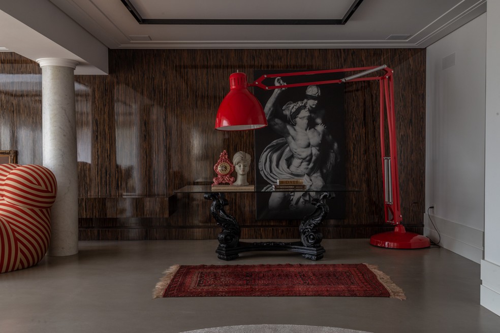 A exuberante luminária vermelha é destaque neste canto do living, ambientado com uma obra assinada pelo arquiteto — Foto: Marcelo Donadussi