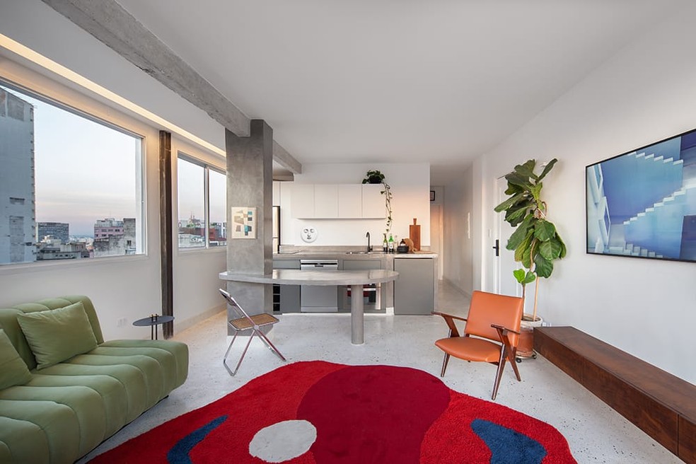 Esta sala de estar, projetada pelo arquiteto Cyro Guimarães, conta com um tapete colorido com formato orgânico — Foto: André Mortatti