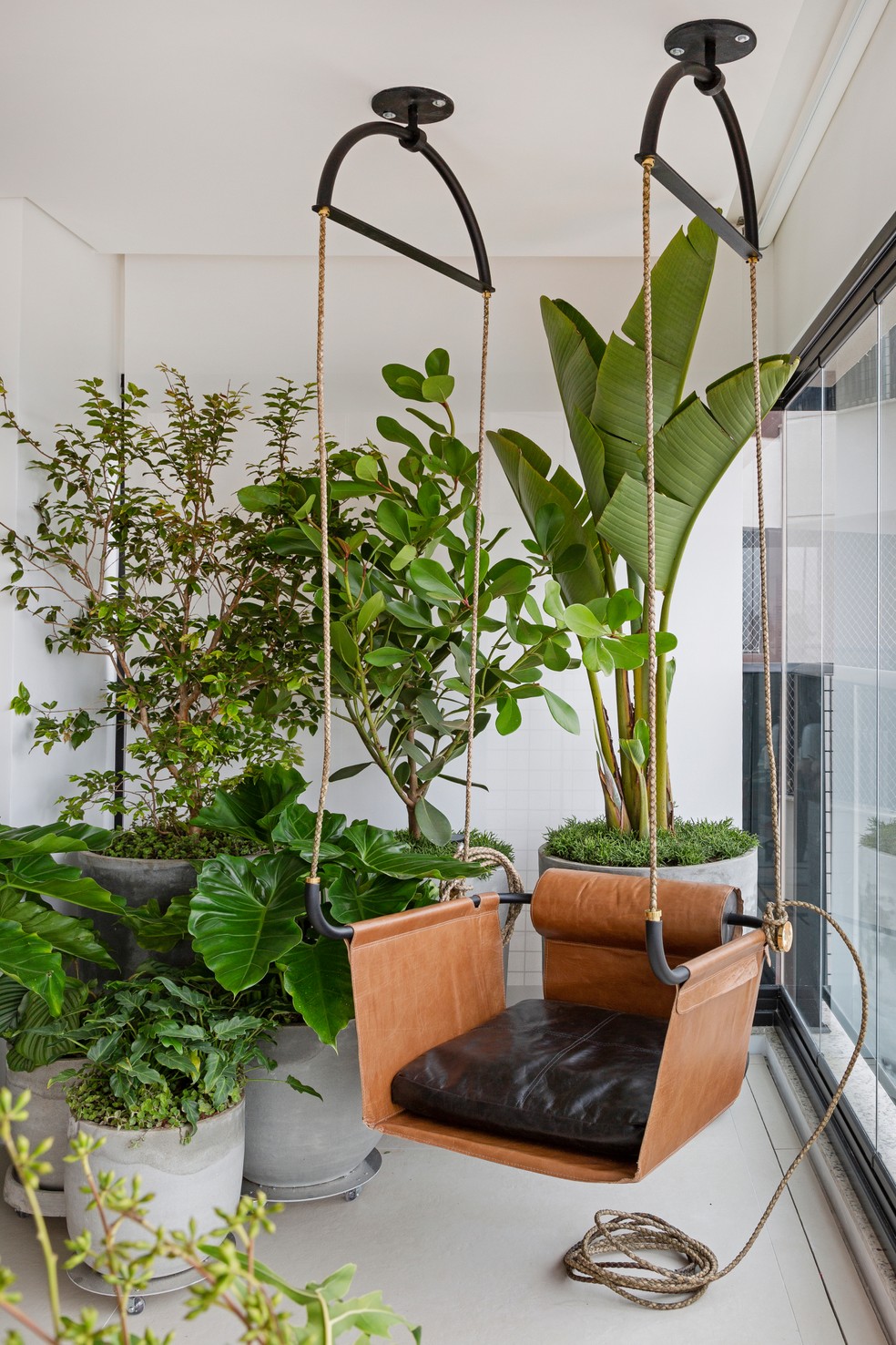 Sala integrada à varanda com jardim de vasos e balanço assinada por Tria Arquitetura — Foto: Julia Ribeiro/Divulgação