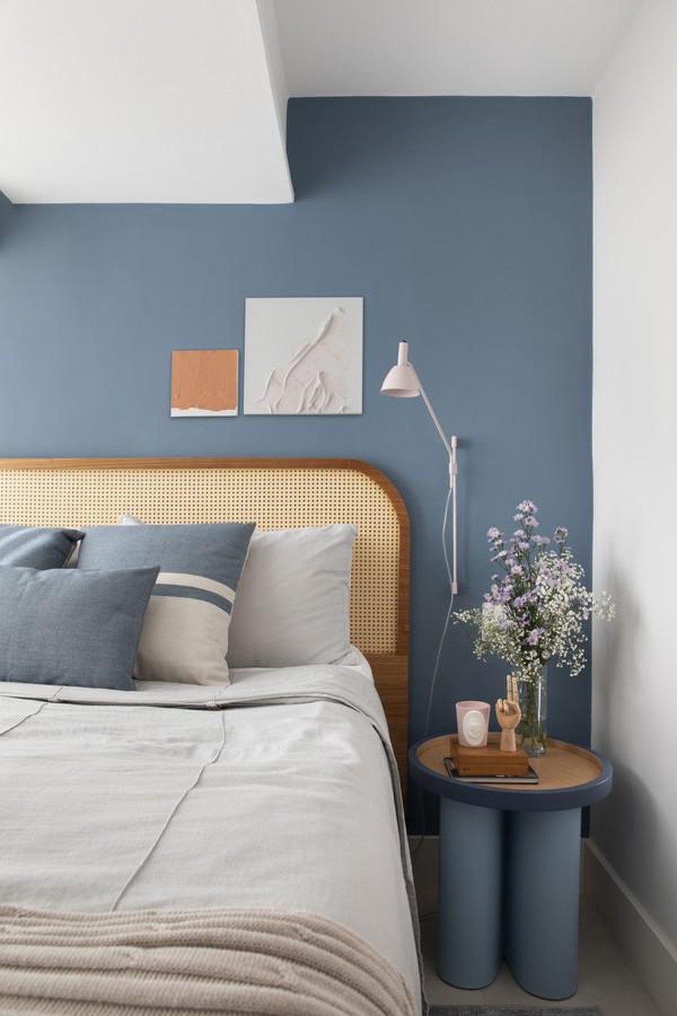 No quarto principal, um azul sereno emoldura a parede da cabeceira. O mesmo tom se repete na mesa lateral (Foto: Denilson Machado/MCA Estúdio) — Foto: Casa Vogue